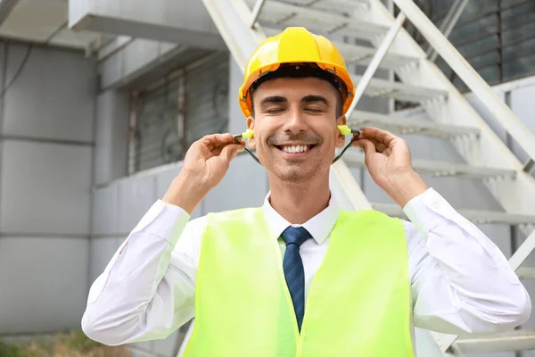 Manlig Byggare Sätta Öronproppar Utomhus — Stockfoto