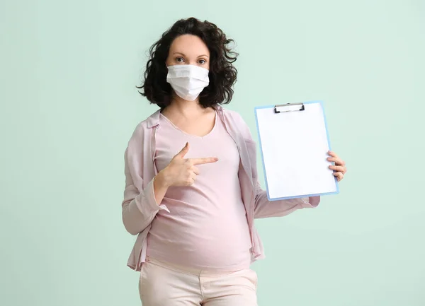 戴医用口罩 带彩色背景剪贴板的年轻孕妇 — 图库照片