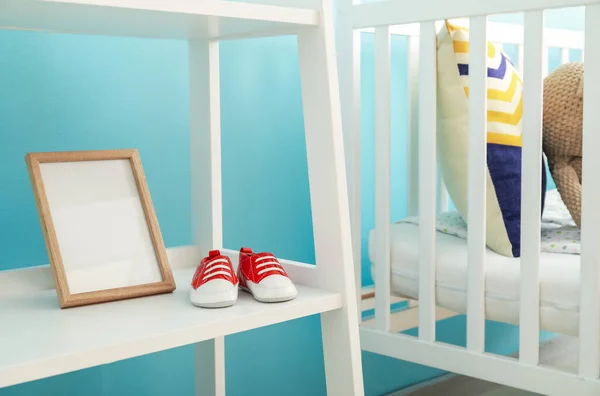 时髦儿童房婴儿鞋放在婴儿床附近的架子上 — 图库照片