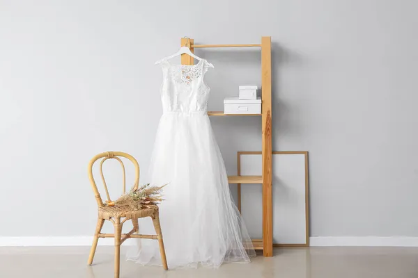 装饰精美的婚纱 挂在架子上 挂在靠轻墙的椅子上 挂着一束鲜花 — 图库照片