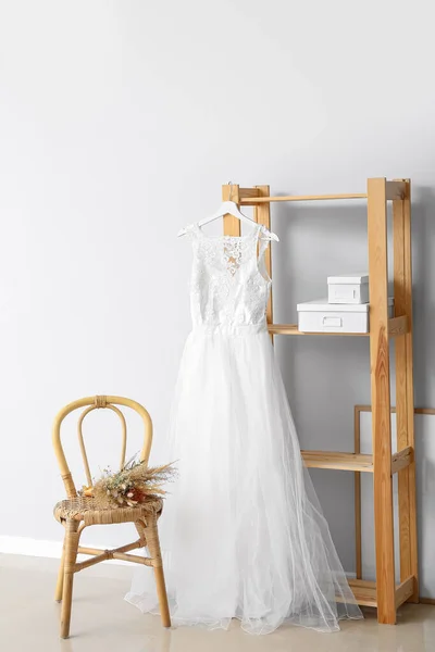 装饰精美的婚纱 挂在架子上 挂在靠轻墙的椅子上 挂着一束鲜花 — 图库照片
