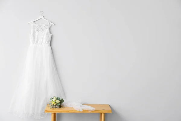 木制桌子 上面挂着一束美丽的花朵和婚纱 挂在轻墙上 — 图库照片