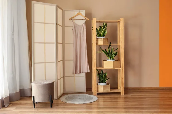 ベージュの壁の近くのドレス 棚ユニット 観葉植物と屏風 — ストック写真
