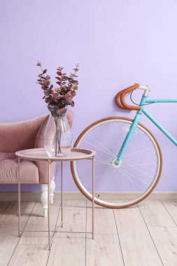 Masalı koltuk ve leylak duvarın yanında bisiklet.