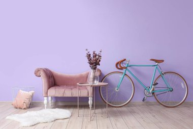 Masalı koltuk ve leylak duvarın yanında bisiklet.
