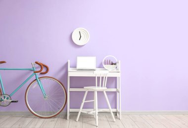 Diz üstü bilgisayarı ve leylak duvarının yanında bisikleti olan modern bir iş yeri