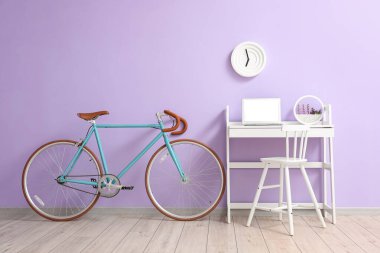 Diz üstü bilgisayarı ve leylak duvarının yanında bisikleti olan modern bir iş yeri