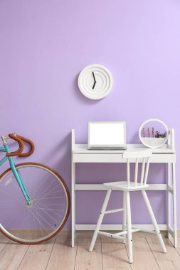 Diz üstü bilgisayarı ve leylak duvarının yanında bisikleti olan modern bir iş yeri