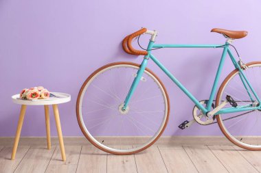 Çiçekli masa ve leylak duvarın yanında bisiklet.