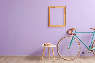 Table with flowers and bicycle near lilac wall clipart