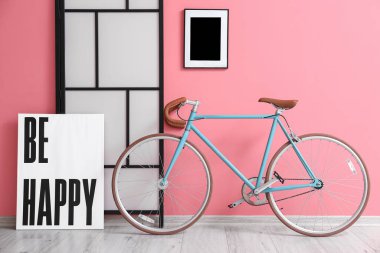Pembe duvarın yanında poster ve katlanmış ekranlı modern bisiklet
