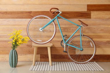 Modern bisiklet, masa ve vazo ahşap duvarın yanında.