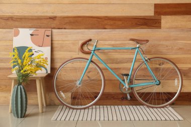 Modern bisiklet, tablo ve vazo ile ahşap duvarın yanında.