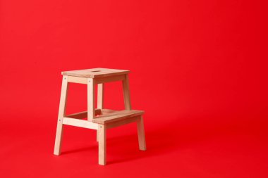 Kırmızı arkaplanda tahta basamak taburesi