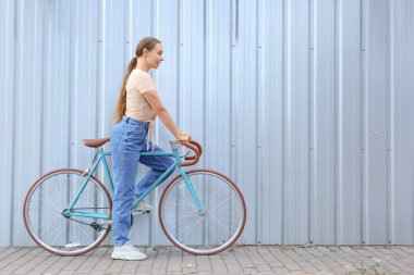 Mavi çitin yanında bisikleti olan güzel genç kız.