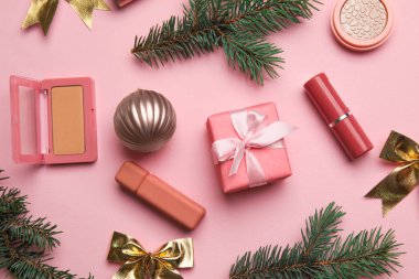 Renk arkaplanındaki makyaj malzemesi ve köknar dallarıyla kompozisyon