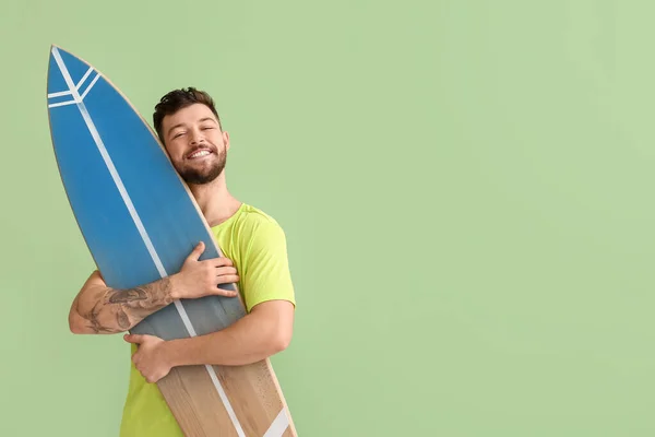 ハンサムなひげそり男抱擁サーフボード上の緑の背景 — ストック写真
