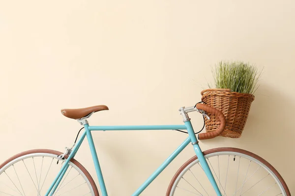 Современный Велосипед Плетеной Корзиной Зеленой Травой Возле Бежевой Стены — стоковое фото