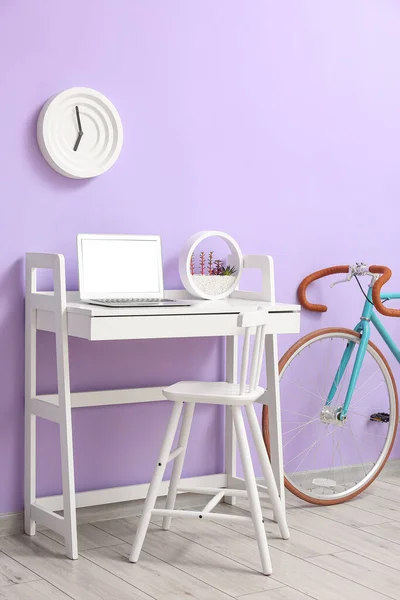 Moderno Lugar Trabajo Con Portátil Bicicleta Cerca Pared Lila — Foto de Stock