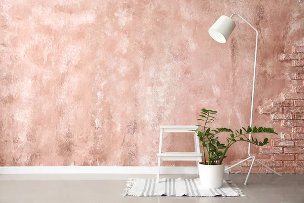 ピンクの壁の近くに立ってランプと観葉植物と白い足踏みスツール — ストック写真