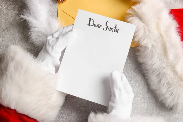 圣诞老公公手上拿着空白的圣诞祝福清单信在灰色的桌子上装饰着圣诞装饰品 特写着 — 图库照片