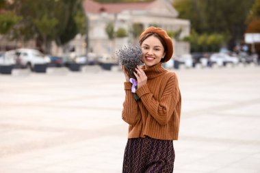 Şehir sokaklarında çiçek açan lavanta çiçekleri olan zarif bir kadın.