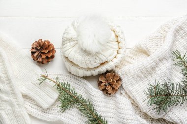 Beyaz ahşap arka planda köknar kozalaklı ve dallı sıcak kıyafetler.