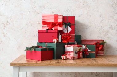 Işık duvarının yanındaki ahşap masada farklı Noel hediyeleri.