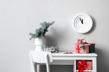 Farklı Noel hediye kutuları ve ışık duvarının yanında köknar ağacı dalları olan bir iş yeri.