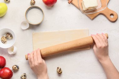 Kadın beyaz arka planda elmalı turta hazırlamak için hamur topluyor.