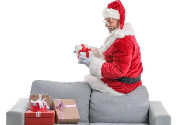 サンタクロースはソファに座って白い背景にギフトボックスを保持 — ストック写真