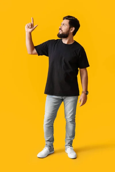 Schöner Mann Schwarzen Shirt Zeigt Auf Etwas Auf Gelbem Hintergrund — Stockfoto