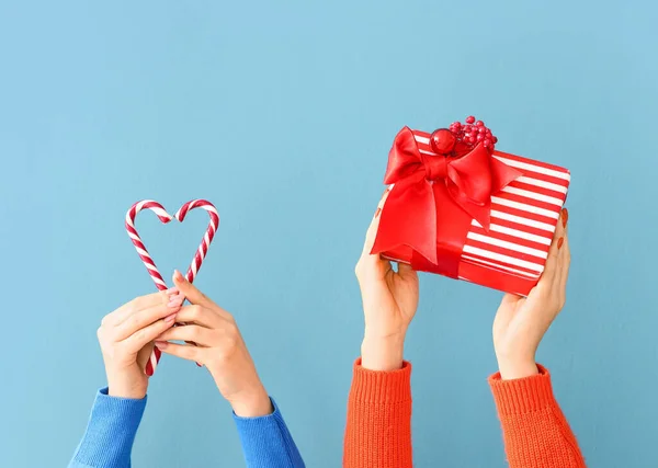 Vrouwelijke Handen Met Kerstcadeau Snoep Stokken Kleur Achtergrond — Stockfoto