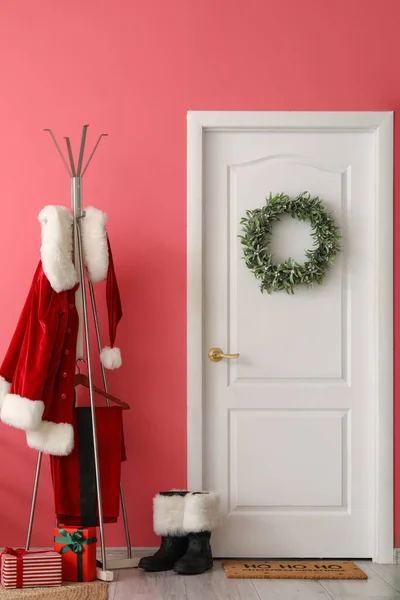 Wieszak Stroju Świętego Mikołaja Buty Pobliżu Białych Drzwi Świątecznym Wieńcem — Zdjęcie stockowe