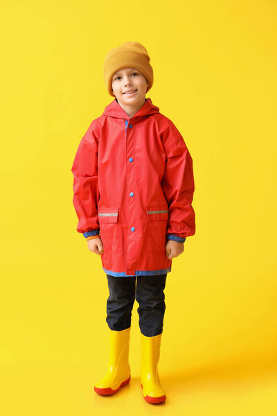 Little boy in raincoat on color background