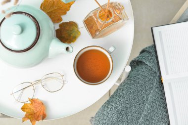 Çay demliği, bir fincan sıcak içecek ve sazlık ayırıcı masada.