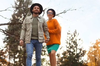 Sonbahar parkında yürüyüş yapan mutlu çift.