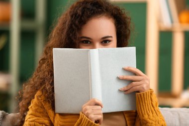 Evde kitabı olan genç bir Afro-Amerikalı kadın.