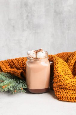 Mason kavanozu tarçınlı lezzetli kahve ve açık arkaplanda sıcak süveter.