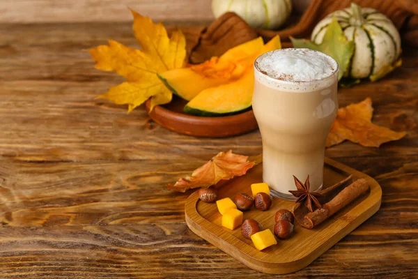 Glass of tasty pumpkin latte on wooden background