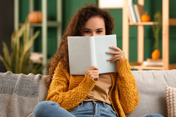 Evde kitabı olan genç bir Afro-Amerikalı kadın.