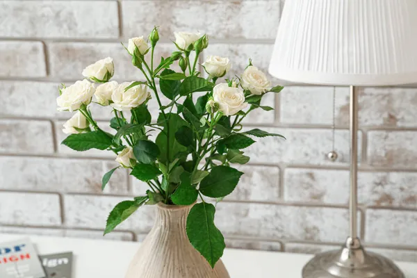 レンガの壁の近くのテーブルの上にバラの花束と花瓶 — ストック写真