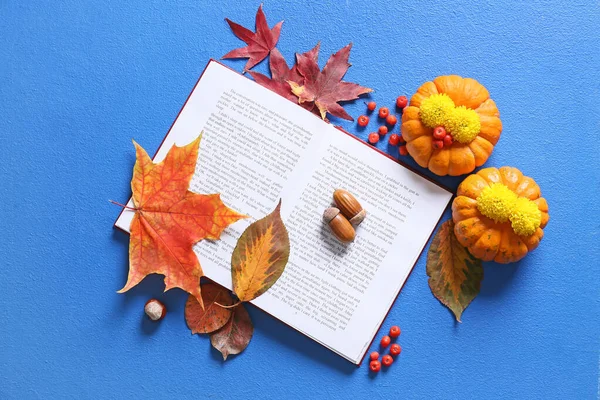 Açık kitap, olgun balkabakları ve renk arkaplanındaki doğal orman dekoruyla kompozisyon