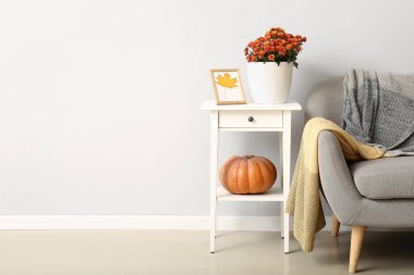 Masada güzel kasımpatı çiçekleri ve ışık duvarının yanında rahat bir kanepesi olan tencere.