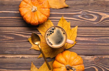 Ahşap arka planda bir fincan lezzetli balkabağı kahvesi ve sebze.