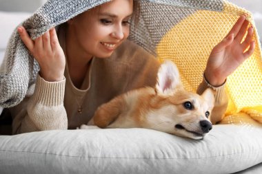 Corgi köpeği olan genç bir kadın evde pouf 'un üzerinde yatıyor.