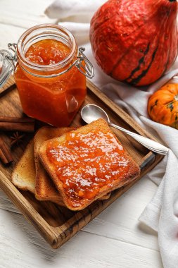 Beyaz ahşap arka planda kızarmış ekmek ile balkabağı reçeli kavanozu