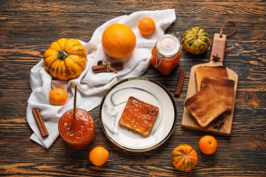 Tatlı kabak reçelli bir tabak tost ve ahşap zemin üzerinde portakallar.