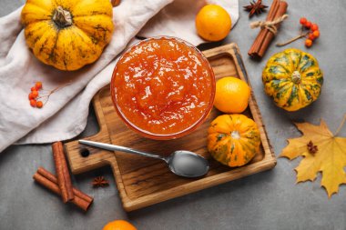 Bir kase tatlı kabak reçeli ve gri arka planda portakallar.