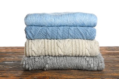 Ahşap masada beyaz arka planda mavi ve gri süveterler